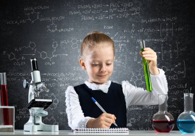 Küçük bilim kadını test tüpünü inceliyor.