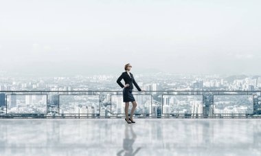 Gökdelenlerin üzerinde gün doğumu ve yeni bir güne bakan iş kadını