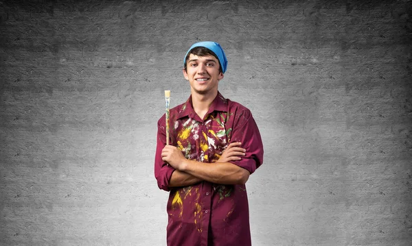 Young happy artist holding paintbrush — Stock Photo, Image