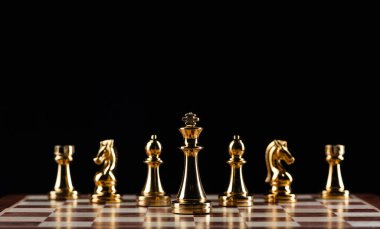 Satranç tahtasında duran altın satranç figürleri