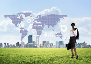 Modern şehir manzarasına karşı yeşil çimlerin üzerinde duran kamera kafalı kadın.