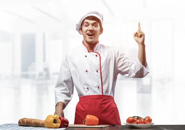 Молодий чоловічий шеф-кухар стоїть біля кухонного столу — стокове фото