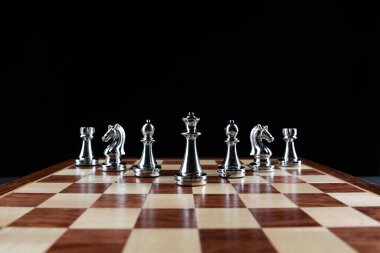 Satranç tahtasının üzerinde duran gümüş satranç figürleri