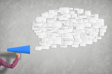 Beton arka planda mavi kağıt trompet tutan bir kadın eli