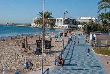 Alicante sahilinde gezinen insanlar İspanya 'da bisiklet sürüyor ve yürüyorlar.