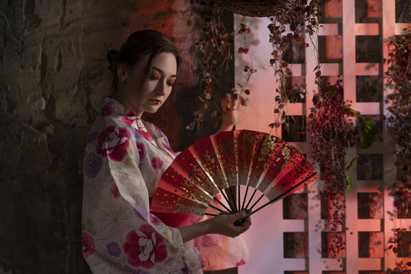 beautiful young woman standing at night in her garden and posing in Japanese kimono alone