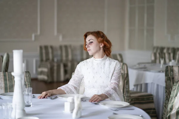 一人で空のレストランで朝食を待っている白いドレスで真剣に病気女性の死亡 — ストック写真