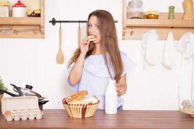 mutfağında poz, ekmek ve çörekler yemek, süt içme ve gülümseyen sevimli tombul kız