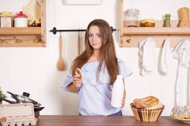 mutfağında poz, ekmek ve çörekler yemek, süt içme ve gülümseyen sevimli tombul kız