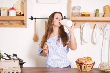 mutfağında poz, ekmek ve çörekler yemek, süt içme ve gülümseyen sevimli tombul kız