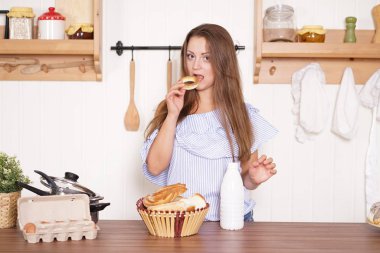 mutfağında poz, ekmek ve çörekler yemek, süt içme ve gülümseyen sevimli tombul kız