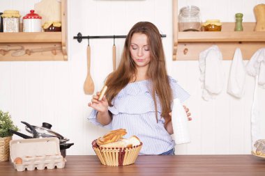 mutfağında poz, ekmek ve çörekler yemek, süt içme ve gülümseyen sevimli tombul kız