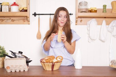 mutfağında poz, ekmek ve çörekler yemek, süt içme ve gülümseyen sevimli tombul kız