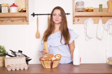 mutfağında poz, ekmek ve çörekler yemek, süt içme ve gülümseyen sevimli tombul kız