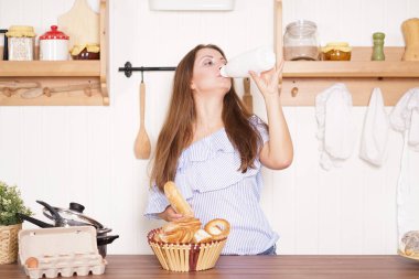 mutfağında poz, ekmek ve çörekler yemek, süt içme ve gülümseyen sevimli tombul kız