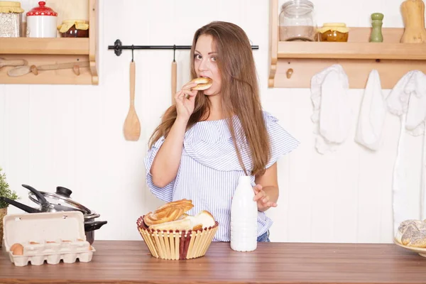 mutfağında poz, ekmek ve çörekler yemek, süt içme ve gülümseyen sevimli tombul kız