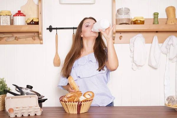 mutfağında poz, ekmek ve çörekler yemek, süt içme ve gülümseyen sevimli tombul kız