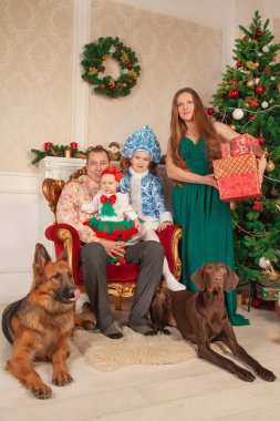 mutlu sevimli festively anne kostümleri ailesinde giyinmiş, baba ve iki kızı birbirlerine hediyeler vermek ve Noel sahiptir