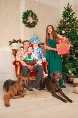 mutlu sevimli festively anne kostümleri ailesinde giyinmiş, baba ve iki kızı birbirlerine hediyeler vermek ve Noel sahiptir