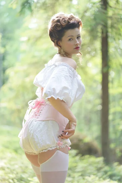 beautiful young chubby girl posing in medieval retro corset and white vintage lingerie in the forest