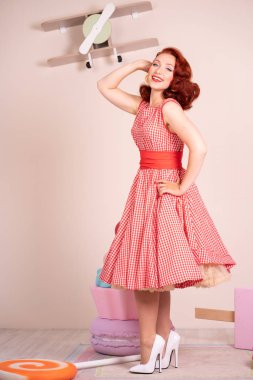 Mutlu kız retro kırmızı bir elbise ve beyaz topuklu poz gülümseyen güzel kızıl saçlı pinup