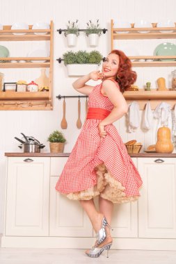 mutlu kız mutfakta yalnız bir retro kırmızı elbiseli poz gülümseyen güzel kızıl saçlı pinup