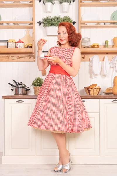 mutlu kız mutfakta yalnız bir retro kırmızı elbiseli poz gülümseyen güzel kızıl saçlı pinup