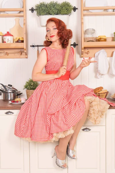 mutlu kız mutfakta yalnız bir retro kırmızı elbiseli poz gülümseyen güzel kızıl saçlı pinup