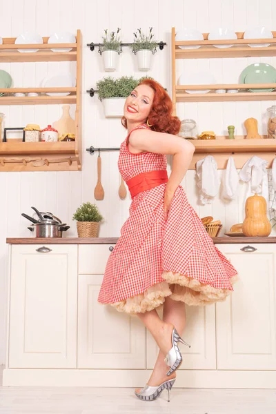 mutlu kız mutfakta yalnız bir retro kırmızı elbiseli poz gülümseyen güzel kızıl saçlı pinup