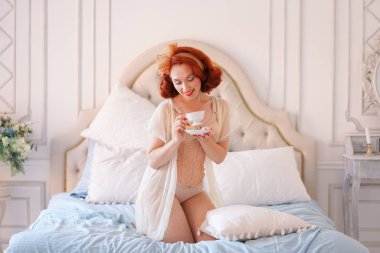 Bayan kadar lüks bir PIN yatak odasında poz bir bej vintage iç çamaşırı giymiş ve kahvaltı çay var