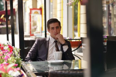 Genç bir işadamı bir kafede yemeğe geldi, bir masada oturur ve birini bekler