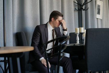 bir telefonla bir kafede oturan bir iş takım elbise, üzgün bir adam. üzüldü.