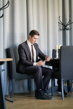 siyah takım elbise, beyaz gömlek ve kravat haber telefonda besleme bakarak bir genç adam