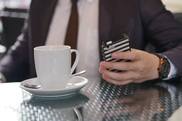 businessman sitting with a Cup of coffee and a phone at a black table with a reflection