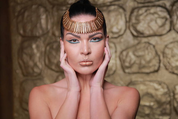 Pretty Tan Brunette Posing. Egypt Style Rich Luxury Woman With Jewellery on Golden Background.
