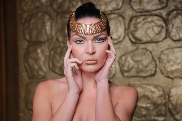 Pretty Tan Brunette Posing. Egypt Style Rich Luxury Woman With Jewellery on Golden Background.