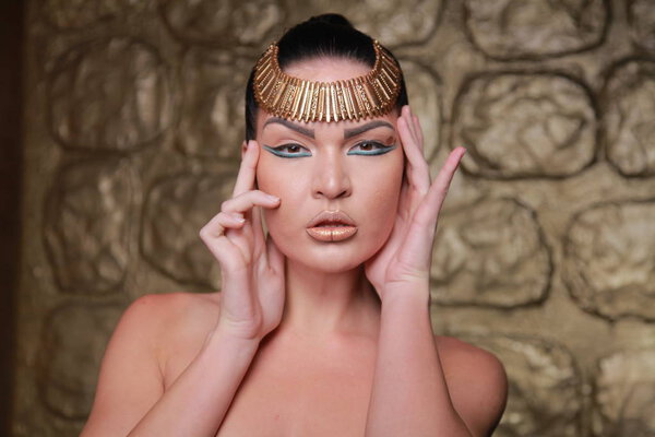 Pretty Tan Brunette Posing. Egypt Style Rich Luxury Woman With Jewellery on Golden Background.