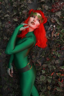 güzel genç kadın Kızıl saçlı yeşil kostüm yaprakları yakınındaki poz