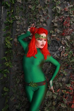 güzel genç kadın Kızıl saçlı yeşil kostüm yaprakları yakınındaki poz