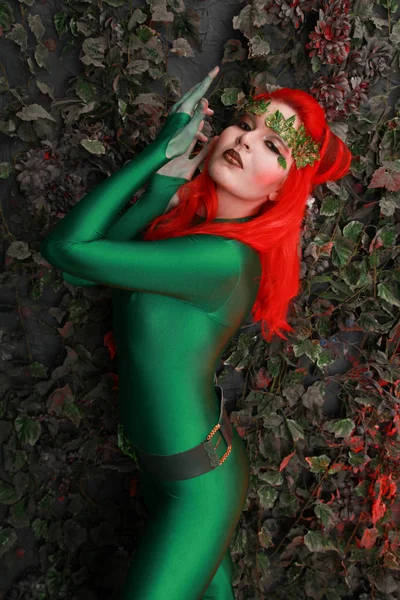 葉に近い緑の衣装でポーズをとって赤い髪と美しい若い女性 — ストック写真