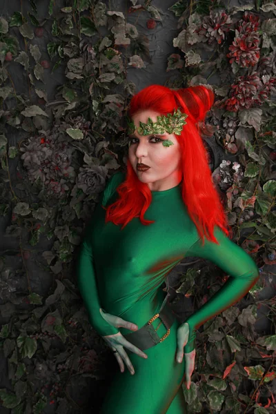 葉に近い緑の衣装でポーズをとって赤い髪と美しい若い女性 ロイヤリティフリーのストック画像