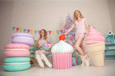 iki şirin arkadaşlarım Pembe pijama yere oturup zevk ve hediyeler ile Noel ağacı yakınındaki gülüyor