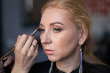 profesyonel makyöz makyaj adım adım bir kadın sarışın yüzünde geçerlidir