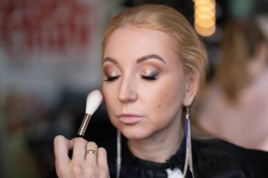 profesyonel makyöz makyaj adım adım bir kadın sarışın yüzünde geçerlidir