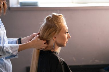 yaparken bir Kuaför ana salonda bir oluklu ve bir perma saçları güzel yetişkin sarışın istemci bir sandalyede oturur