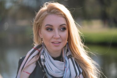 çok güzel sarışın kadın bir deri ceket, siyah elbiseli ve kareli bir bej eşarp ile şehir etrafında yürür ve olumlu hayatına sahiptir