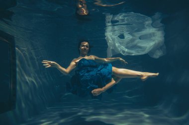 şirin sportif kadın yüzer su altında ücretsiz bir dalgıç gibi mavi bir akşam yalnız elbise