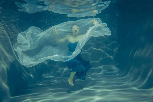 优雅漂亮的女人游泳水下像一个自由潜水员在蓝色晚礼服单独 — 图库照片