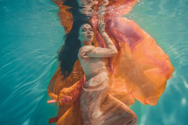 rüya gibi ve meditative reenkarnasyon önce ruh gibi su altında yüzen olan Turuncu elbise kız