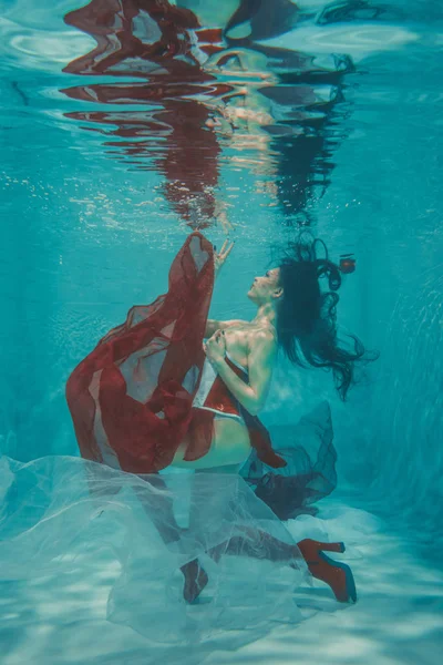 beautiful sexy girl swimming underwater in sporty style red and white fetish corset and over knee thigh high boots with heels